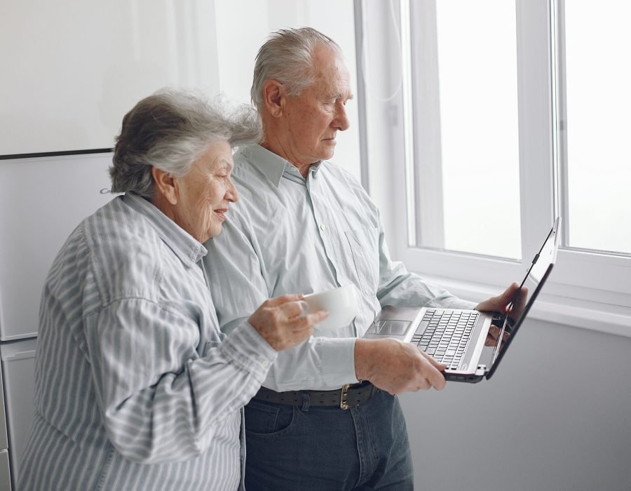 Grandparents at home. Old people use the laptop. Senior in a blue shirt.
