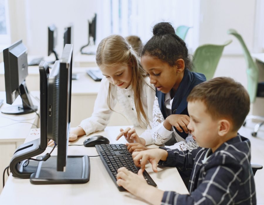 Guy and the girl are sitting at the table. African girl in computer science class. Kids playing computer games.